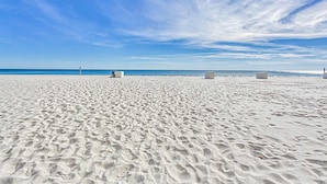A wide sandy beach with a clear sky and a calm sea. - Waterfront home with a private deck, gas grill, WiFi, & central AC (Gulf Shores)