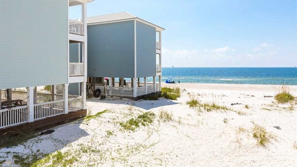 Una proprietà fronte spiaggia con un edificio a due piani, un portico coperto e vista sull'oceano.
