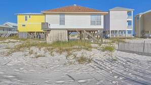 Una proprietà fronte spiaggia con una casa su palafitte, un edificio giallo e un edificio bianco con balcone.