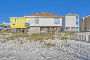 Ein Anwesen direkt am Strand, mit einem Haus auf Stelzen, einem gelben Gebäude und einem weißen Gebäude mit Balkon.