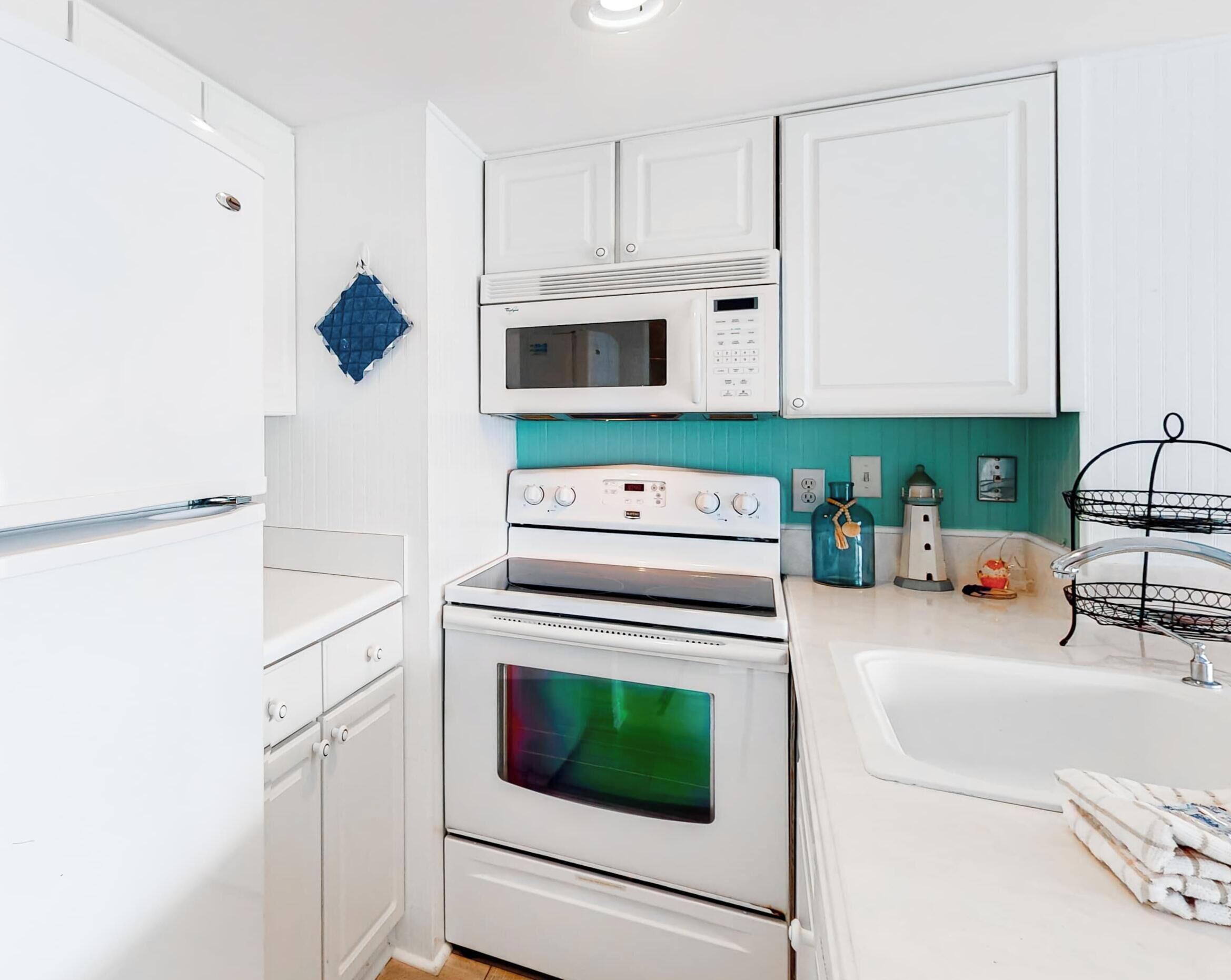 A kitchen with white cabinets, a microwave, a stove, and a sink.
