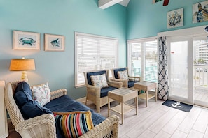 A room with wicker furniture, a lamp, and framed artwork on the walls.
