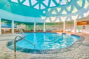 An indoor swimming pool with a clear ceiling and tiled floor.