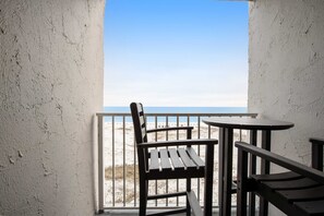 Ein Balkon mit Blick auf den Strand, ein Holzstuhl und ein kleiner Tisch.