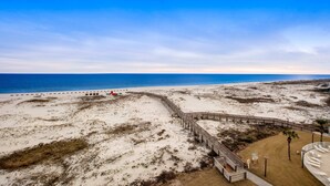 A beach with a wooden boardwalk leading to a sandy area, a clear sky, and the ocean in the background. - Fifth floor oceanfront studio with central AC, WiFi, pools and gym (Fort Morgan)