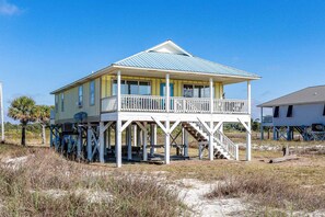 A beachfront house with a balcony, a covered porch, and a staircase leading to the upper level. - Dog-friendly home near the beach with grill, central AC & balcony (Fort Morgan)
