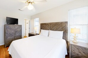 A hotel room with a bed, a television on a dresser, a ceiling fan, and a nightstand with a lamp. - Dog-friendly home near the beach with grill, central AC & balcony (Fort Morgan)