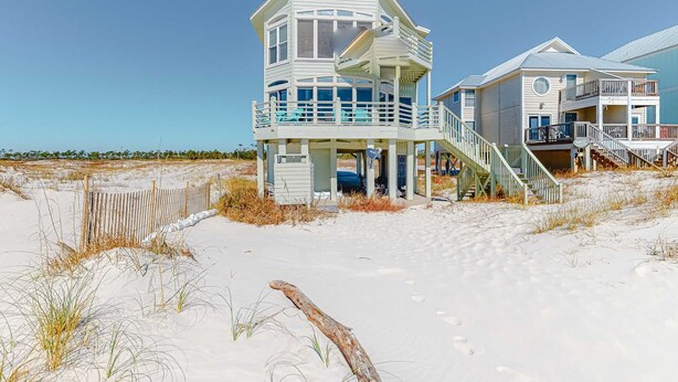 Una casa sulla spiaggia con struttura a più livelli, un balcone e una scala che conduce al piano superiore.