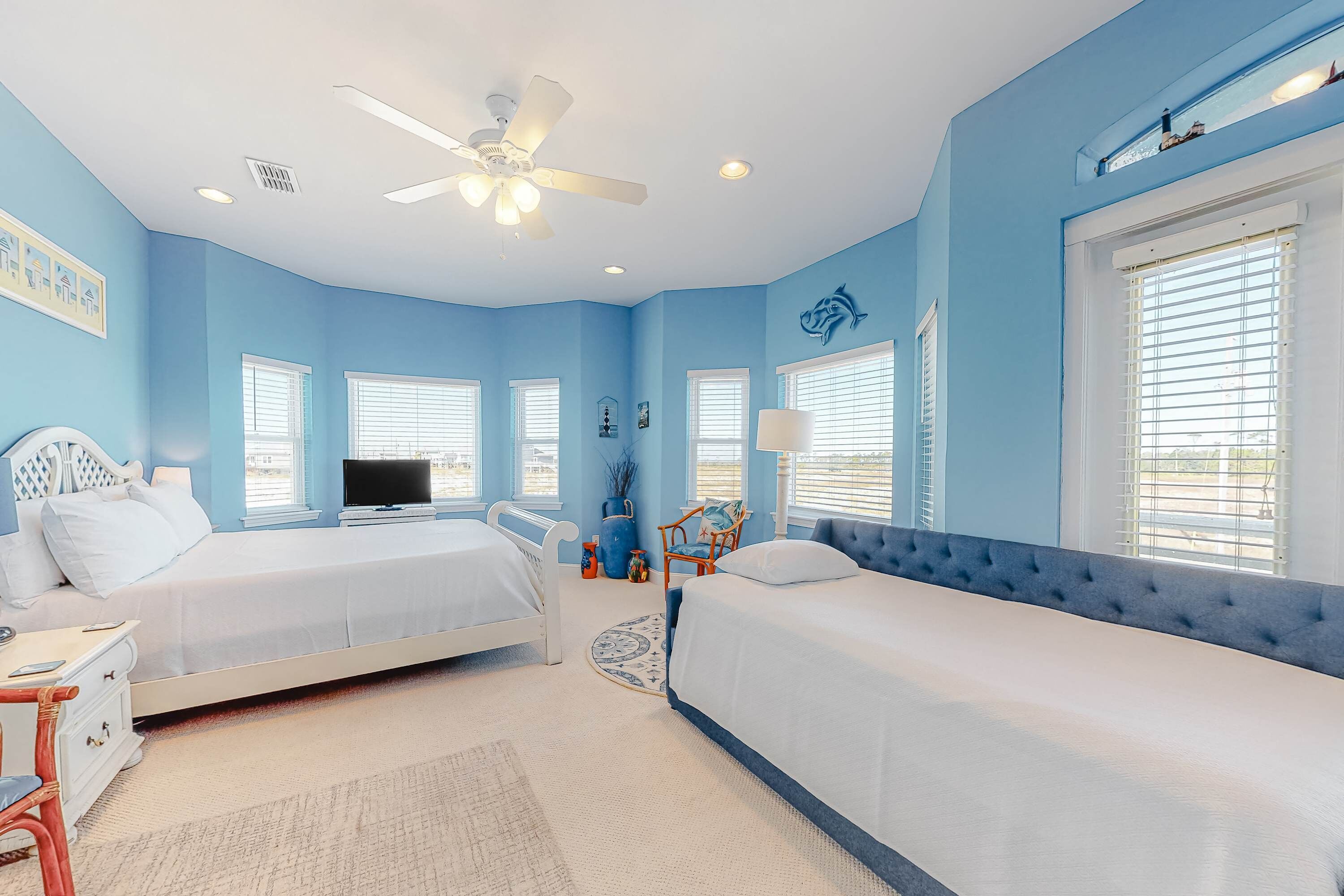 A bedroom with two beds, a ceiling fan, and a TV.