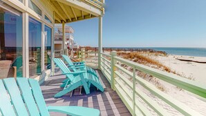 Un balcone vista mare con sedie e un pontile in legno.