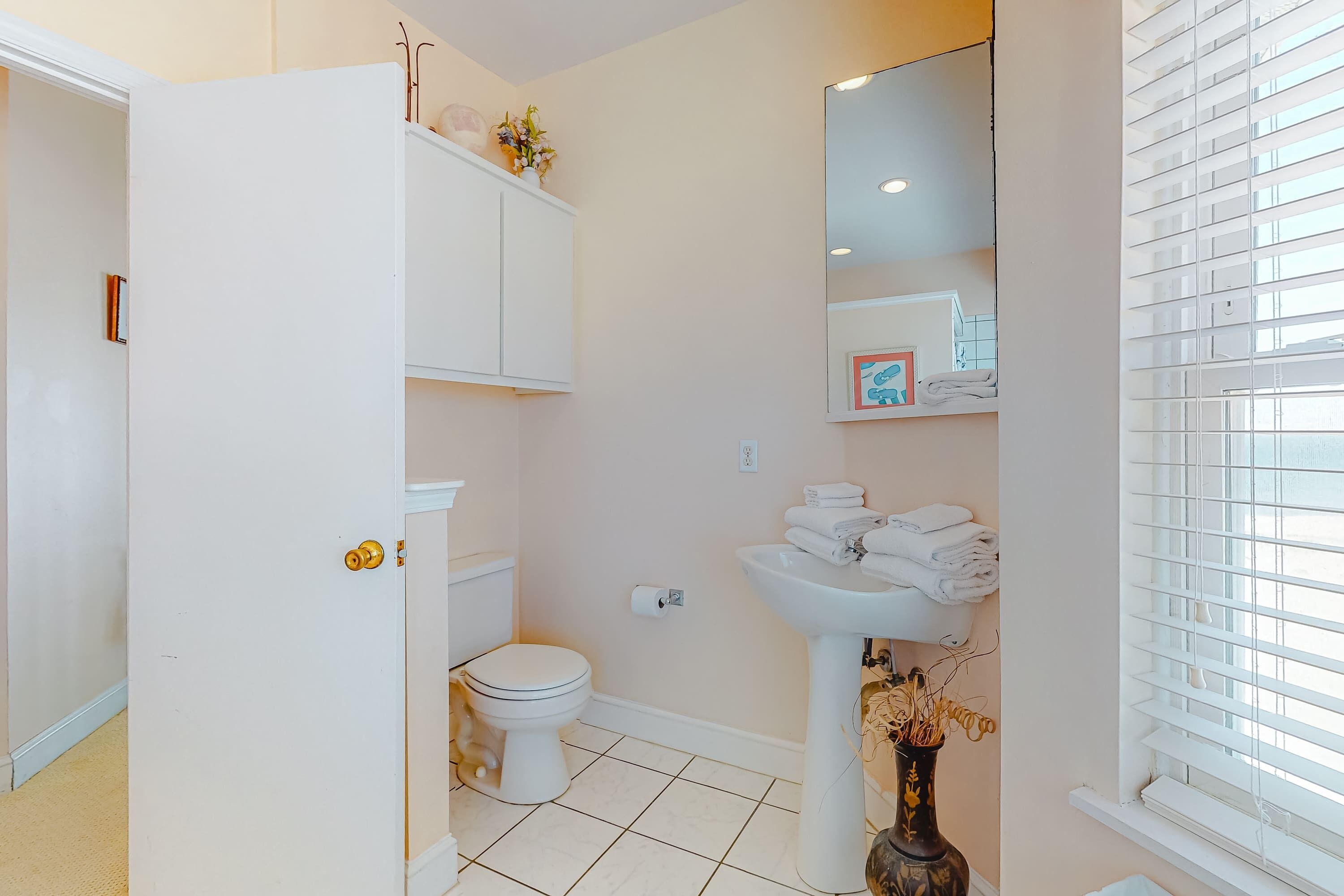 A bathroom with a toilet, sink, and a white cabinet.