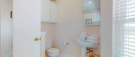 A bathroom with a toilet, sink, and a white cabinet.