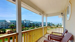 Ein Balkon mit Holzgeländern, einer Bank und Blick auf ein Wohngebiet mit Gebäuden und Grünflächen.