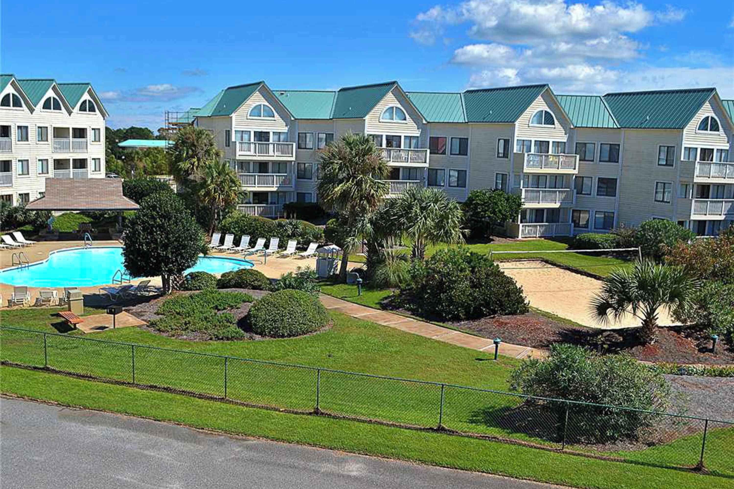 A hotel with multiple-story buildings, a swimming pool, and well-maintained lawns.