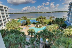 A resort with a pool, palm trees, and a view of the water. - Spacious condo with pool & hot tub - tennis available on-site (Gulf Shores)