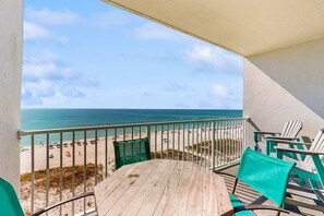 Ein Balkon mit Blick auf den Strand, einem Tisch und zwei Stühlen.