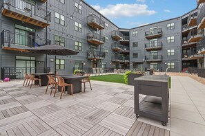 Ein moderner Außenbereich mit Holzdeck, einer Bar mit Sitzgelegenheiten und einem kleinen Garten.