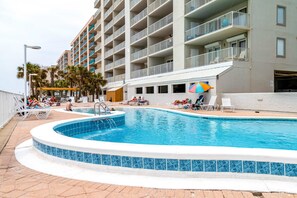 Ein Hotel mit Swimmingpool, mehreren Balkonen und Palmen.