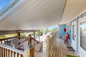 A covered outdoor area with a wooden deck, a staircase, and a view of the parking lot. - Fun Seahorse condo with gas grill, W&D, & pool access - walk to West Beach (Gulf Shores)
