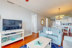 A modern living room with a TV, sofa, and coffee table. - Beautiful Gulf Shores Home w/Shared Pool, Hot Tub, and Sauna + Free WiFi (Gulf Shores)