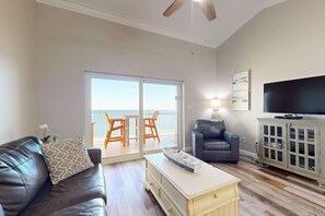 Una sala de estar con sofá, mesa de centro, televisor, mueble y balcón con vistas.
