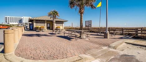A paved walkway with benches, a small building, and a flagpole.