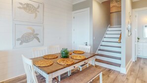 Ein Essbereich mit einem Holztisch, weißen Stühlen und gewebten Tischsets.