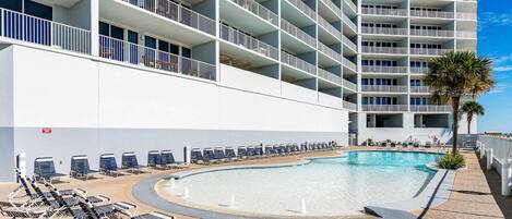 Un hotel con varios balcones, piscina y tumbonas.
