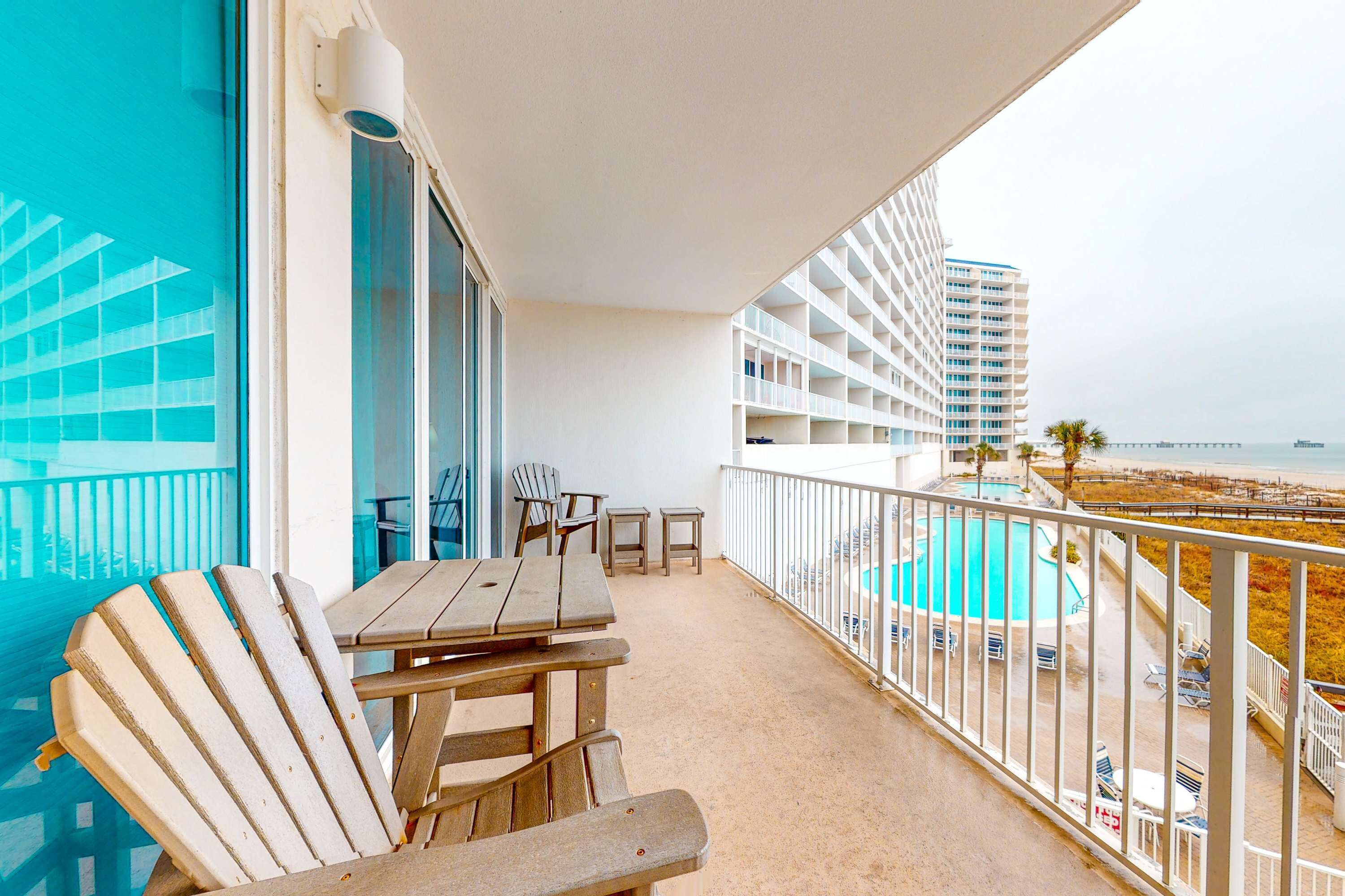 A balcony with a pool, chairs, and a table.