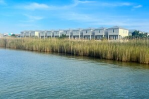 A row of modern, multi-story buildings with a flat roof design, situated adjacent to a body of water. - Luxurious, two-story cottage near the beach w a full kitchen & shared pool (Gulf Shores)