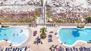 A resort with two swimming pools, sun loungers, and a central walkway. - Beachfront condo with amazing views, multiple on-site pools & hot tubs (Gulf Shores)