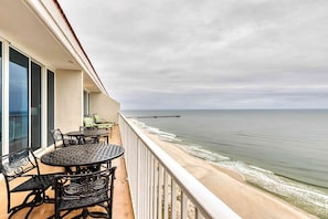 A balcony with a table and chairs, overlooking a beach and a pier. - Beachfront penthouse w/ amazing view, multiple pools, hot tubs, gym & sauna (Gulf Shores)