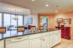 A kitchen with a large island, white cabinetry, and a view to the outside. - Beachfront penthouse w/ amazing view, multiple pools, hot tubs, gym & sauna (Gulf Shores)