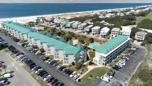 A coastal hotel with multiple buildings, a parking lot, and a beach view. - Cozy waterfront getaway with pools, hot tub & tennis courts (Fort Morgan)