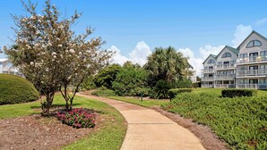 A landscaped pathway leading to a building with multiple balconies and a well-maintained garden. - Cozy waterfront getaway with pools, hot tub & tennis courts (Fort Morgan)