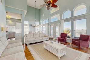 A spacious living area with a sofa, armchairs, a coffee table, and a dining table. Large windows provide ample natural light and views. - Beautiful Water Front Home in Historic Fairhope (Fairhope)