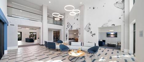 A spacious living area with a high ceiling, modern furniture, and a large flat-screen TV.