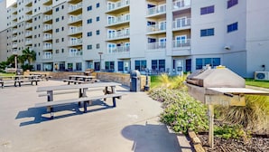 Un edificio residencial de varios pisos con balcones, mobiliario exterior y una parrilla.