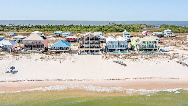 Una propiedad frente a la playa con varias casas, una playa de arena y vista al océano.