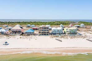 A beachfront property with multiple houses, a sandy beach, and a view of the ocean. - Luxury Beachfront Estate in Fort Morgan | Private Pools, Elevators and Wedding-Friendly (Fort Morgan)