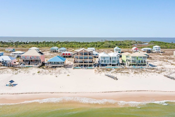 A beachfront property with multiple houses, a sandy beach, and a view of the ocean. - Luxury Beachfront Estate in Fort Morgan | Private Pools, Elevators and Wedding-Friendly (Fort Morgan)