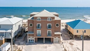 Un edificio multifamiliar frente a la playa con una entrada central, balcones y ubicación junto a la costa.