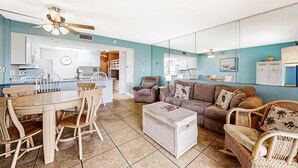 A living room with a dining table, chairs, a sofa, and a coffee table. - Ground-floor condo with entertainment, shared pool, hot tub - near beach (Fort Morgan)