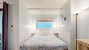 A bedroom with a bed, a window, a lamp, and a wall-mounted decoration. - Waterfront retreat with Gulf views, pools (Fort Morgan)