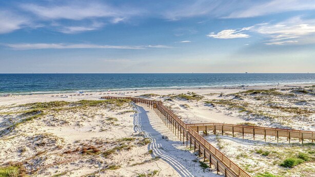 A sandy beach with a wooden boardwalk leading to the ocean. - Waterfront retreat with Gulf views, pools (Fort Morgan)