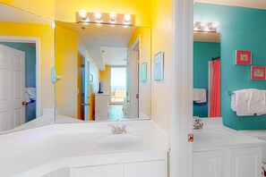 A bathroom with a large mirror, a sink, and a shower area. - Spacious and Conveniently Located Condo Near Beach with Shared Pool & Hot Tub (Fort Morgan)