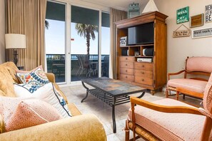 Ein Wohnzimmer mit Sofa, Sessel und einem Holzschrank mit Fernseher.