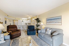 Ein Wohnzimmer mit einem braunen Liegesessel, einem blauen Sessel, einem grauen Sofa, einem Couchtisch und einem Gemälde mit Strandmotiv.