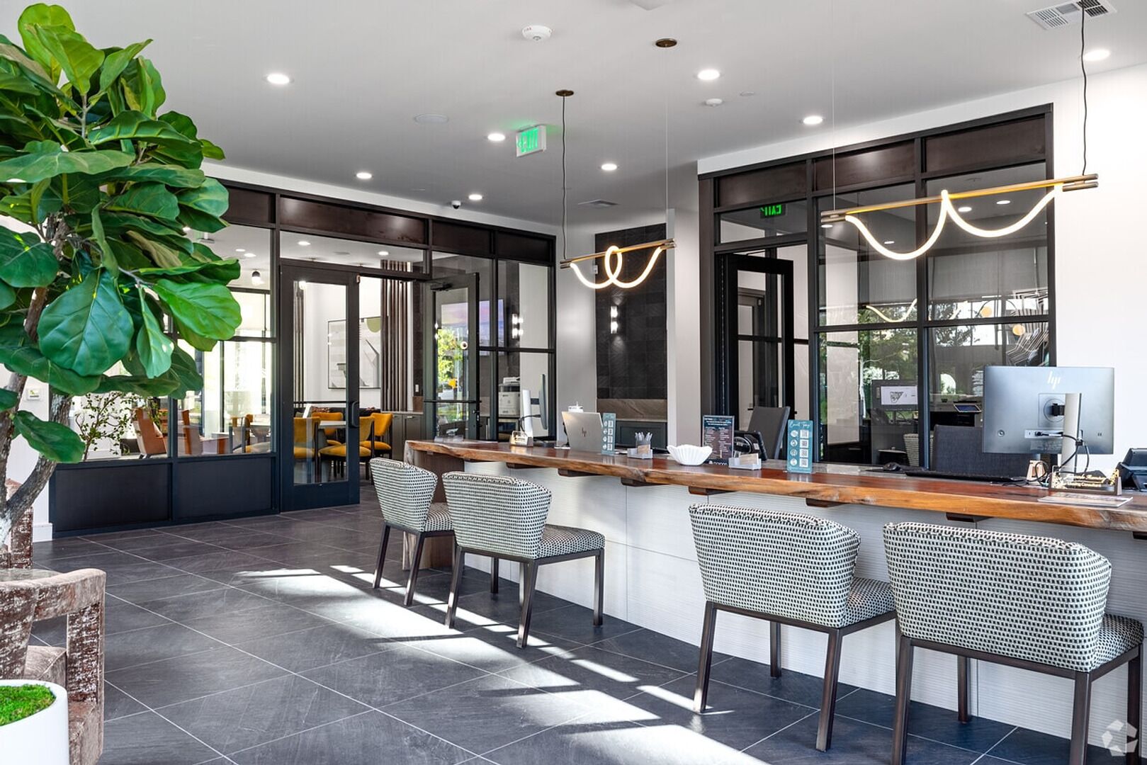 A modern bar area with a wooden counter, bar stools, and a large mirror.