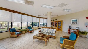 Eine geräumige Lobby mit Korbmöbeln, großen Fenstern und einem Bücherregal.